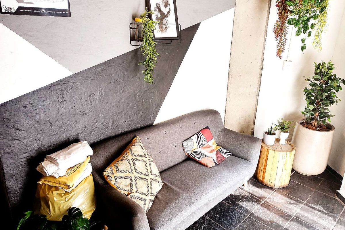 A living area featuring dark tiled flooring and a geometric painted feature wall with a concrete structural column.
