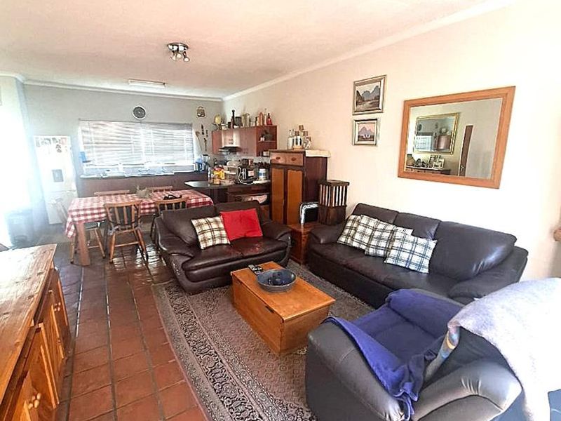Open-plan living and dining area featuring terracotta floor tiles and a functional kitchen layout, offering a comfortable and practical living space.