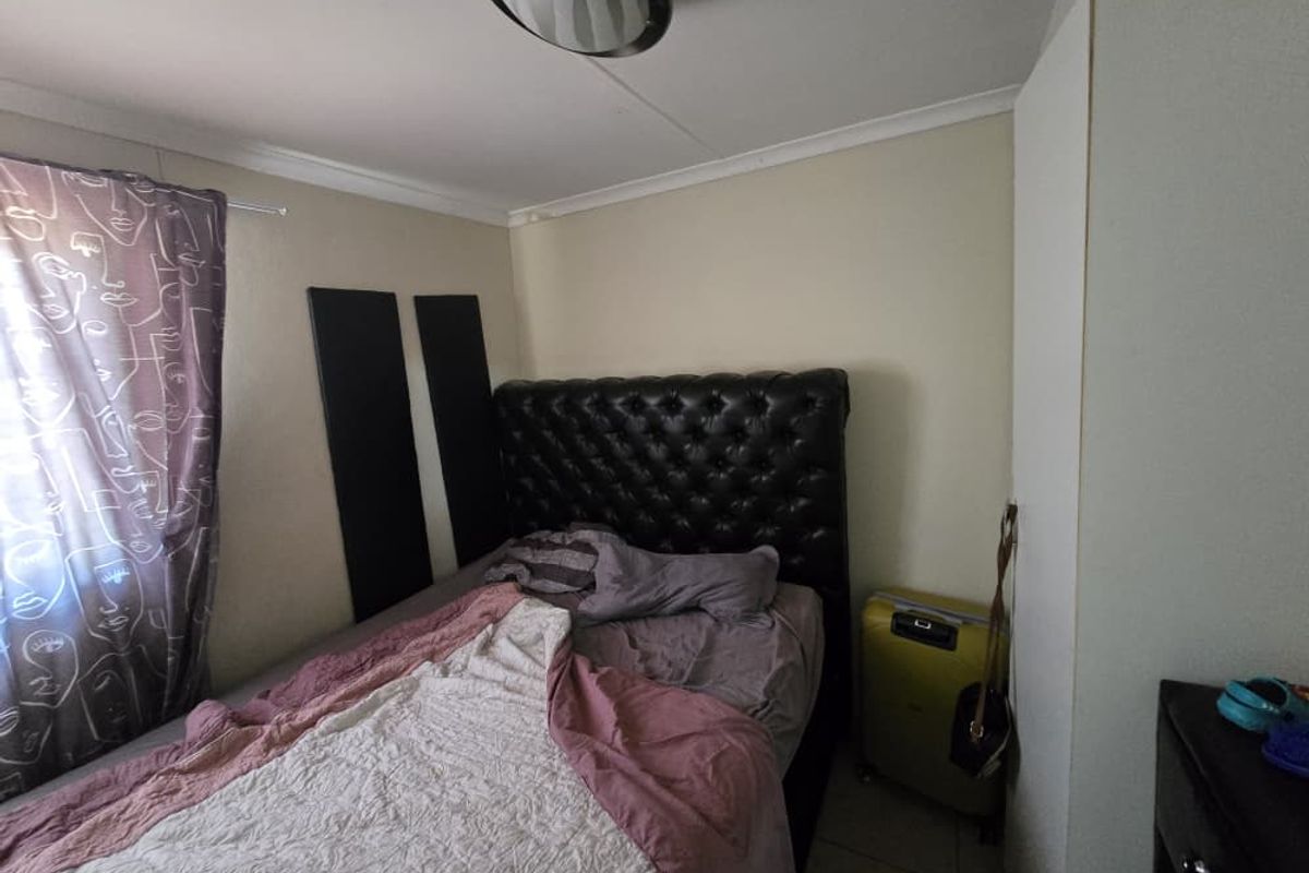 A bedroom featuring tiled flooring, a built-in cupboard, and a ceiling-mounted light fixture.