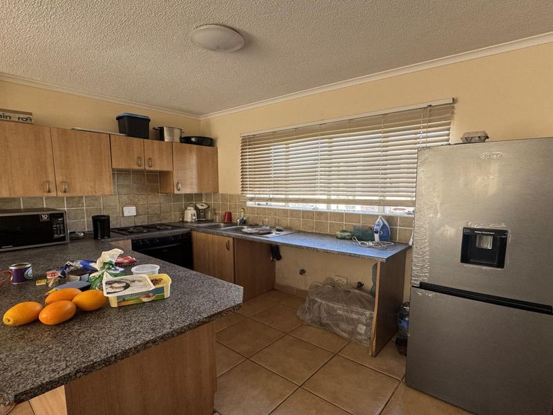 A functional kitchen featuring laminate cabinetry, granite countertops, a built-in oven, and tiled flooring, with an open space for a dishwasher or additional storage.