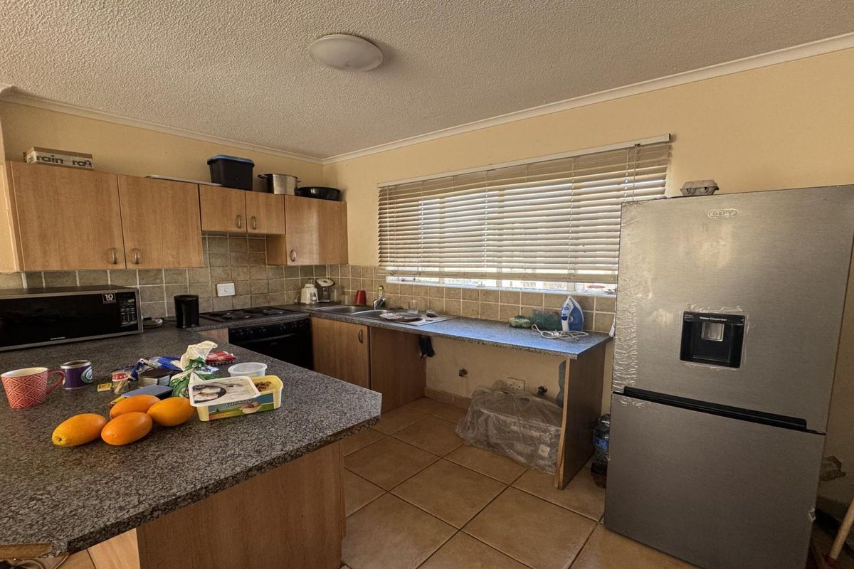 A functional kitchen featuring laminate cabinetry, granite countertops, a built-in oven, and tiled flooring, with an open space for a dishwasher or additional storage.