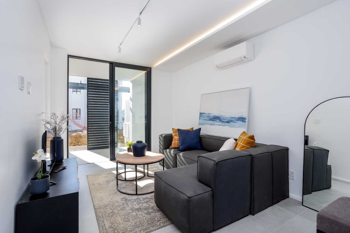Modern living room featuring tiled flooring, recessed ceiling lighting, a split-system air conditioner, and large sliding glass doors leading to an outdoor area.
