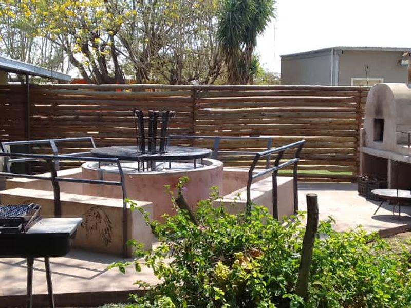 Outdoor entertainment area featuring a built-in fire pit, masonry pizza oven, and paved patio space, ideal for social gatherings.