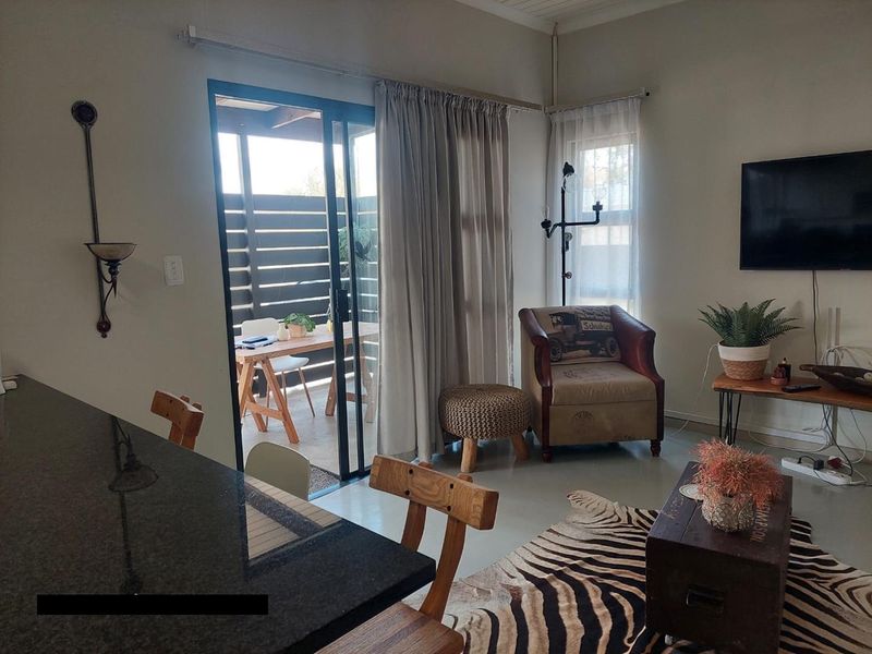Open-plan living area featuring polished concrete floors, a granite kitchen counter, and sliding glass doors providing direct access to an outdoor patio space.