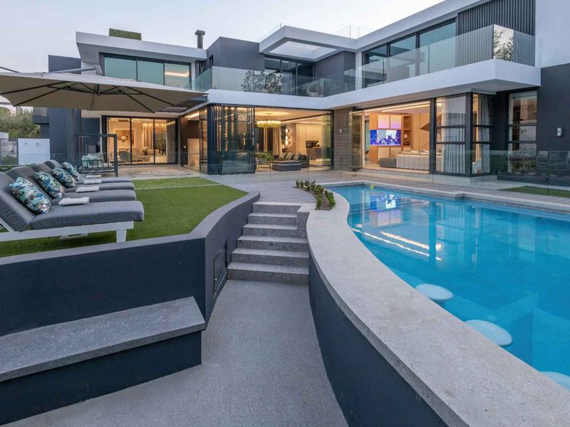 Modern luxury residence featuring a seamless indoor-outdoor flow, a pristine swimming pool with integrated seating, and expansive glass sliding doors.