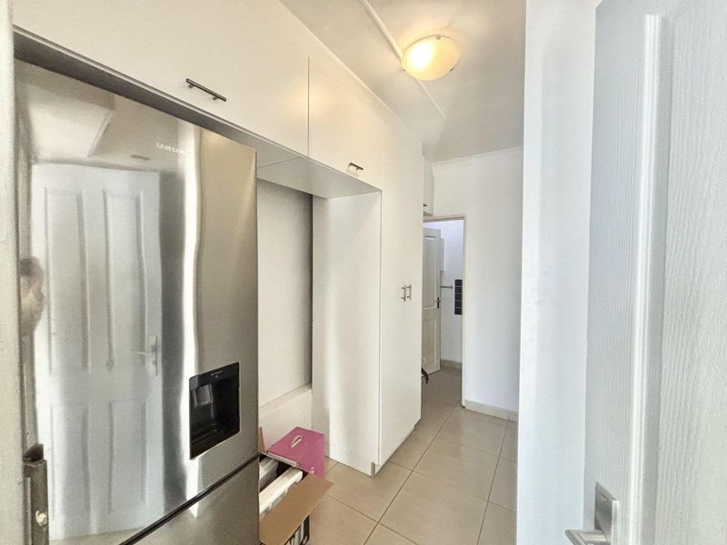 A functional kitchen area featuring white built-in cabinetry and tiled flooring, providing a clean and practical space for food preparation and storage.