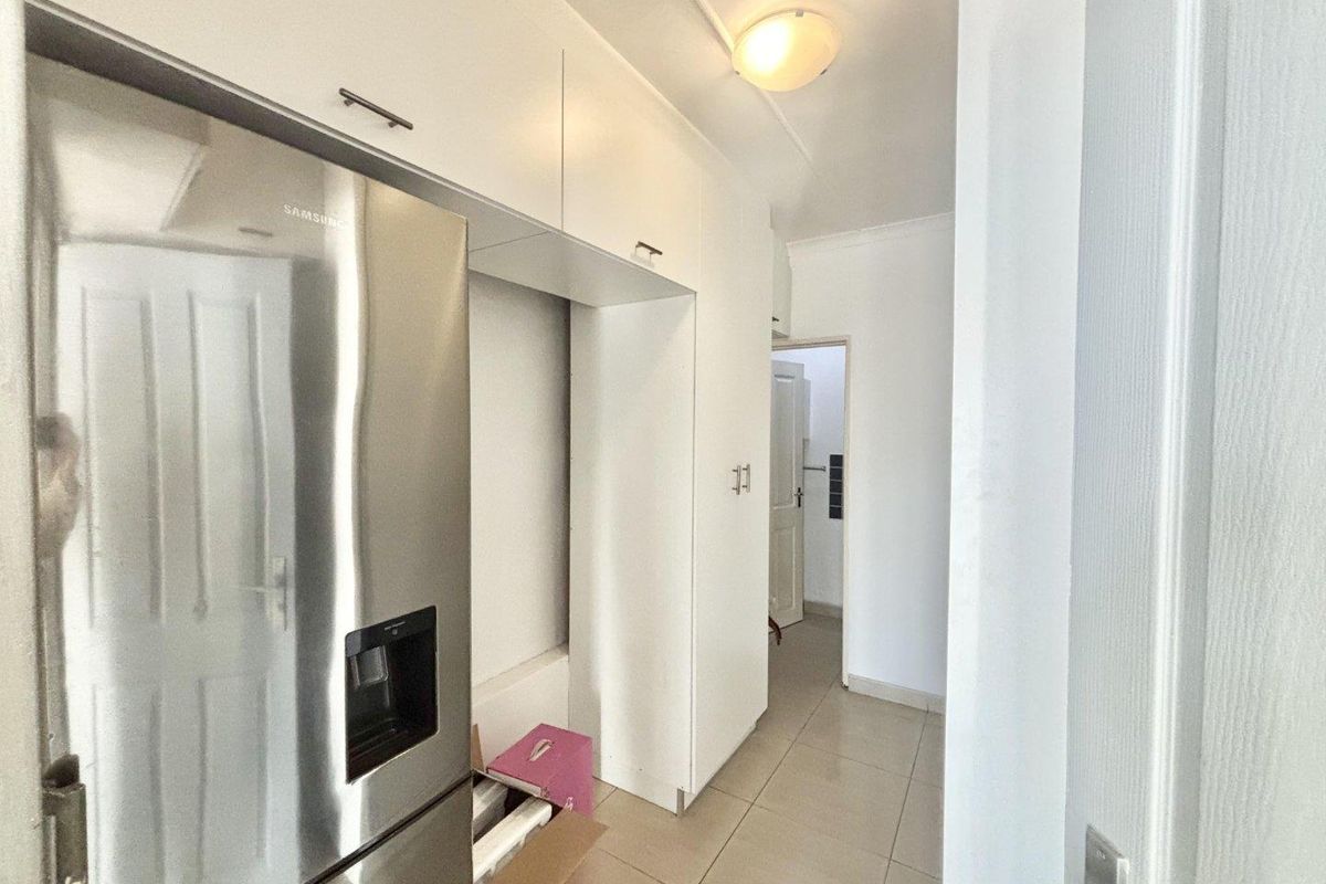 A functional kitchen area featuring white built-in cabinetry and tiled flooring, providing a clean and practical space for food preparation and storage.
