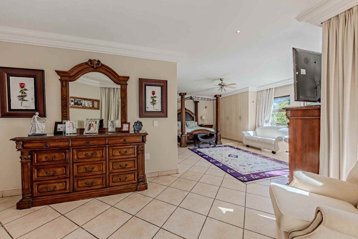 Spacious bedroom featuring tiled flooring, built-in cupboards, and crown molding, offering a comfortable and well-maintained living space.