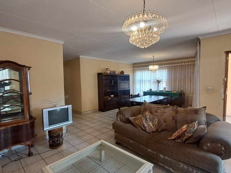 Spacious open-plan living and dining area featuring tiled flooring, coved ceilings, and decorative crystal chandeliers, offering a versatile layout for family living.
