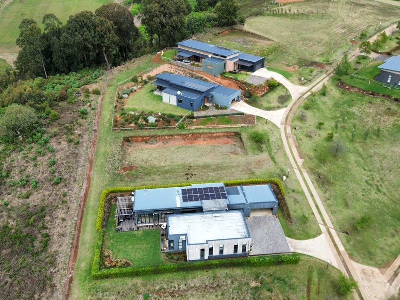 Aerial view of a residential estate featuring modern homes with solar panels, paved driveways, and established garden landscaping.