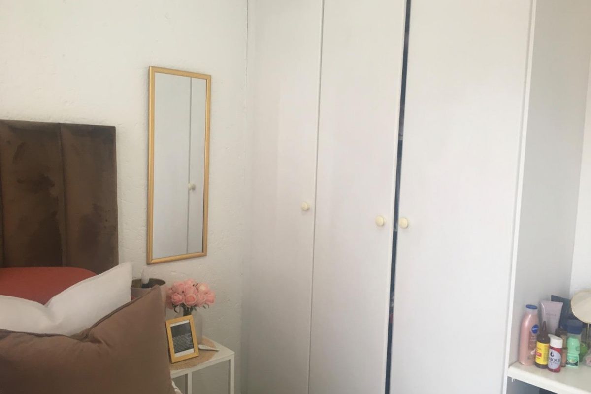 A bedroom featuring built-in white cupboards with simple round knobs, providing functional storage space.