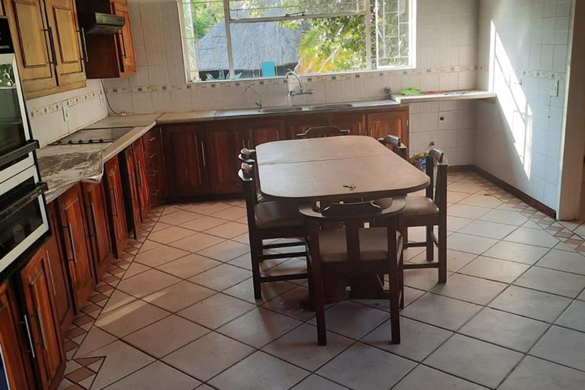 Spacious kitchen featuring wooden cabinetry, built-in oven, hob, and tiled flooring, offering a functional layout with potential for modern updates.