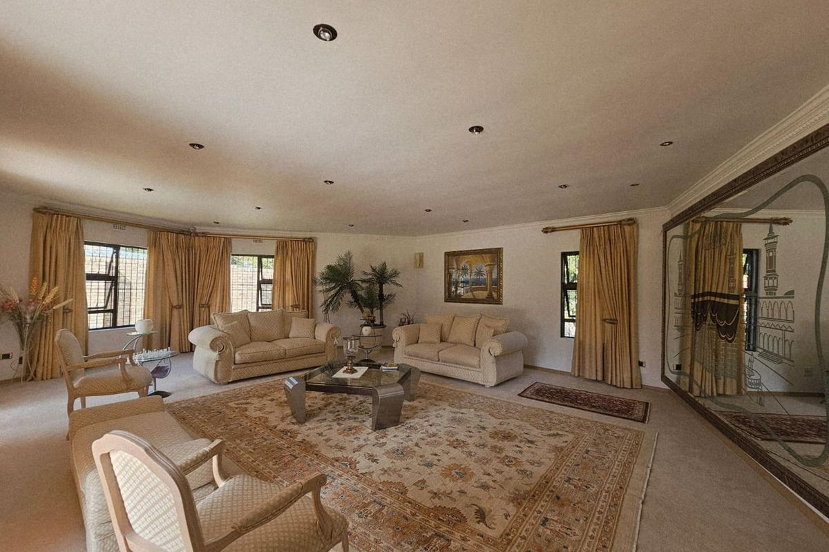 Spacious living room featuring recessed downlighting, large windows with security bars, and a large wall-mounted decorative mirror.