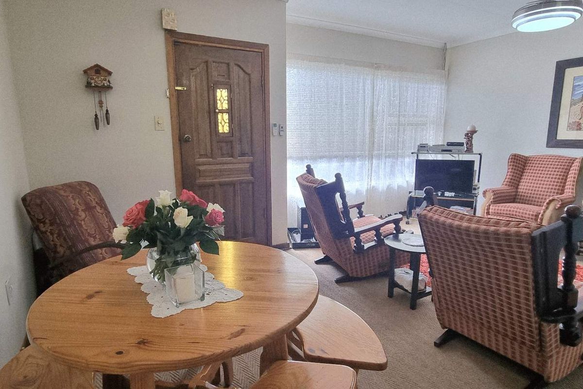 A living room area featuring a solid timber entrance door, carpeted flooring, and large window with natural light.