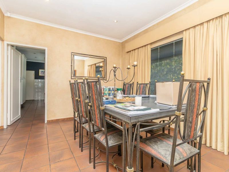 A dining room featuring tiled flooring, coved cornicing, and recessed downlights, providing a functional space for family meals.