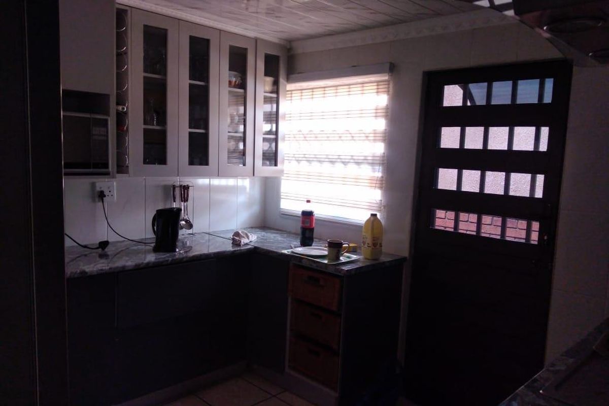 A functional kitchen featuring built-in cabinetry, marble-effect countertops, and a glass-paneled exterior door, providing a practical workspace with natural light.