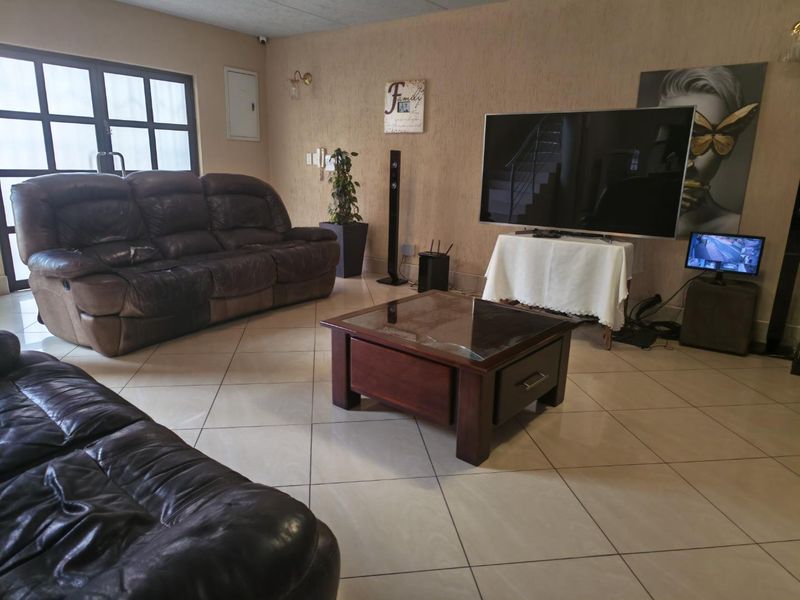 A spacious living room featuring neutral tiled flooring and textured wall finishes, providing a comfortable and functional area for relaxation.