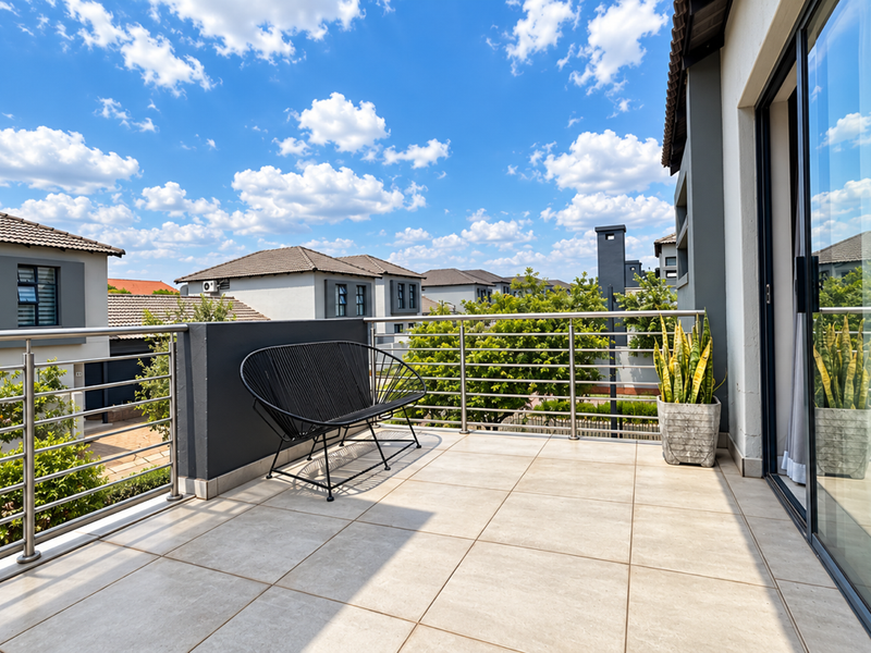 A modern, well-maintained balcony featuring tiled flooring and a stainless steel balustrade, offering a clear view of the surrounding residential area.
