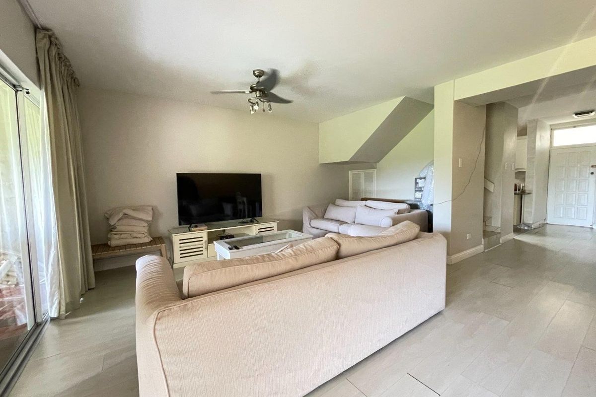 Spacious living room featuring a ceiling fan, neutral flooring, and direct access to an outdoor area via sliding glass doors.