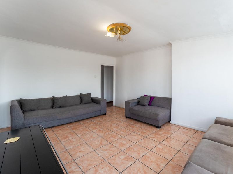 A spacious living room featuring neutral white walls and traditional terracotta-style floor tiles, providing a blank canvas for interior design updates.