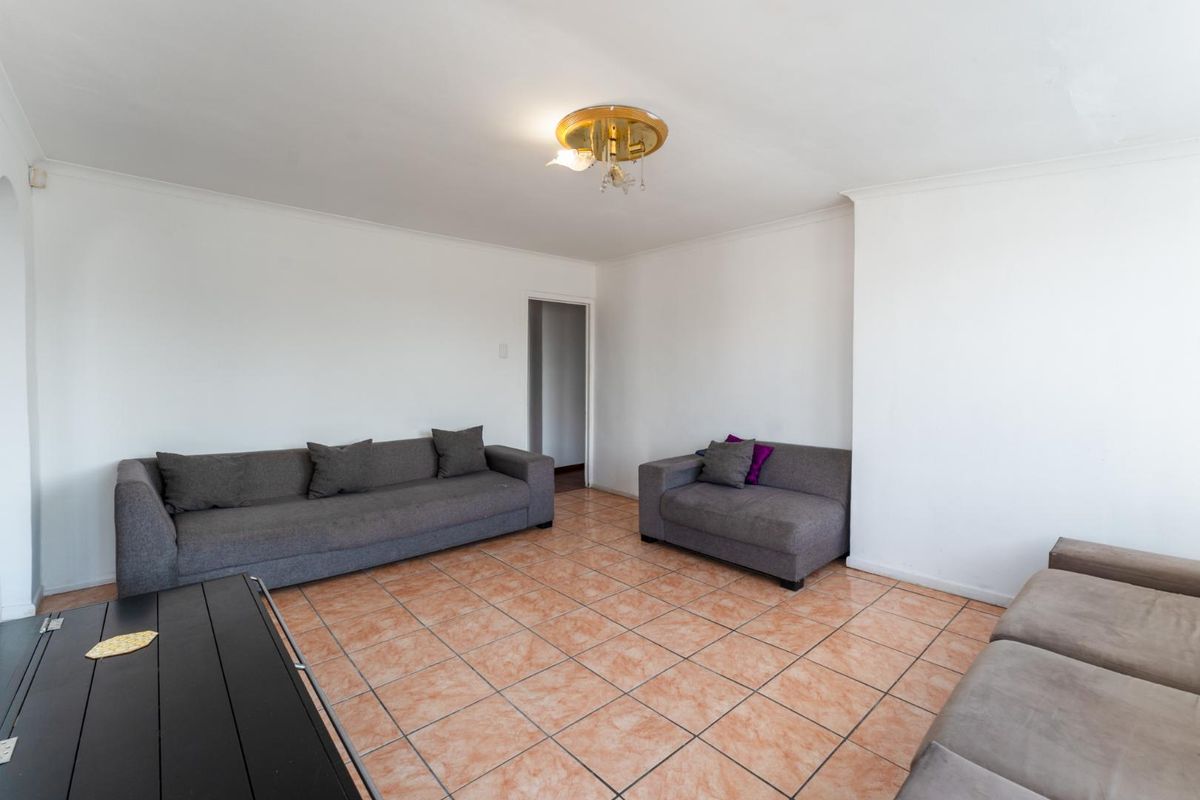 A spacious living room featuring neutral white walls and traditional terracotta-style floor tiles, providing a blank canvas for interior design updates.