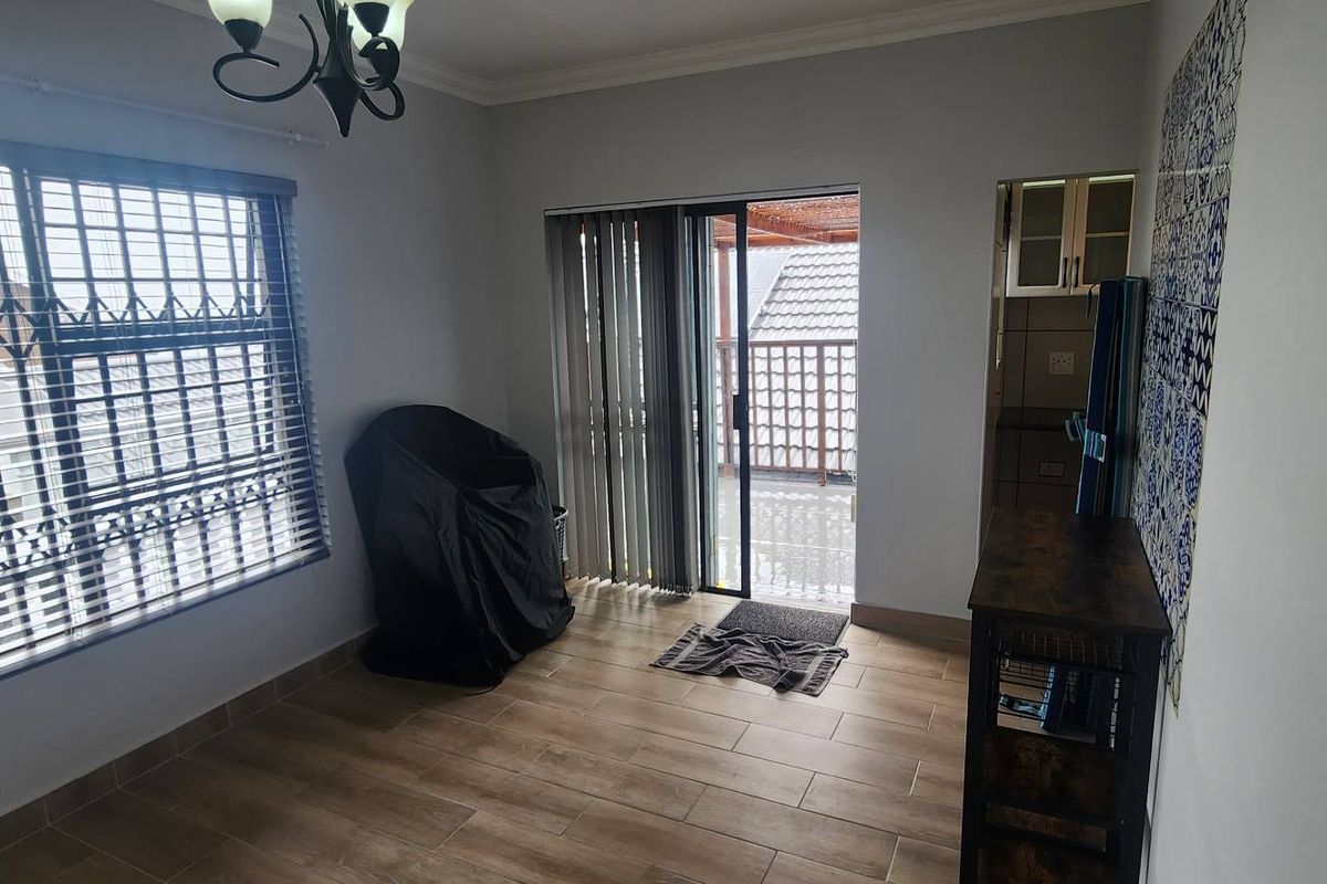 A living area featuring tiled flooring, security bars on windows, and sliding door access to an outdoor patio area.