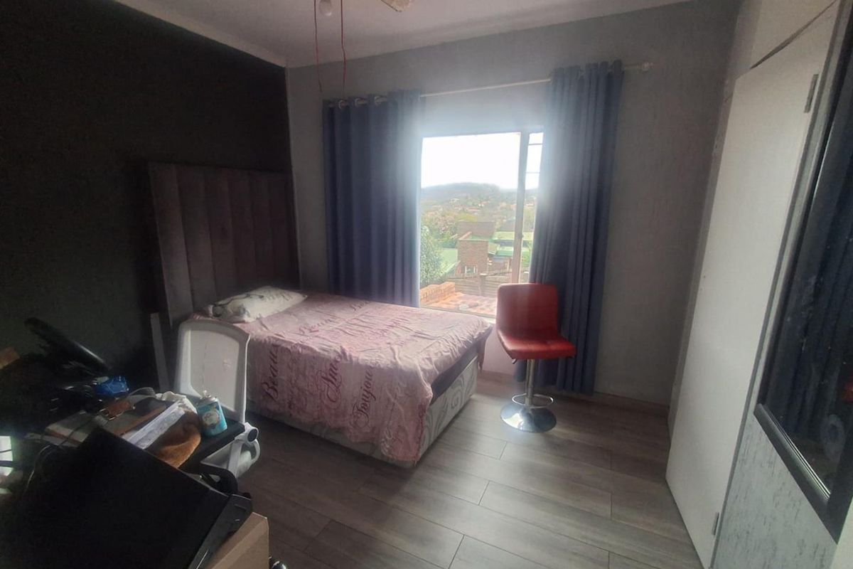 A bedroom featuring laminate flooring, a ceiling fan, and a built-in cupboard, with a window offering an elevated view.