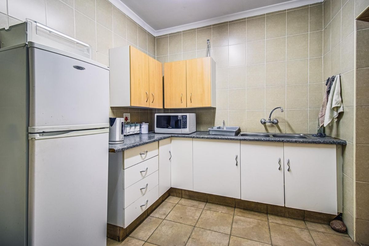 A functional kitchen area featuring built-in cabinetry, a double basin sink, tiled walls, and tiled flooring.