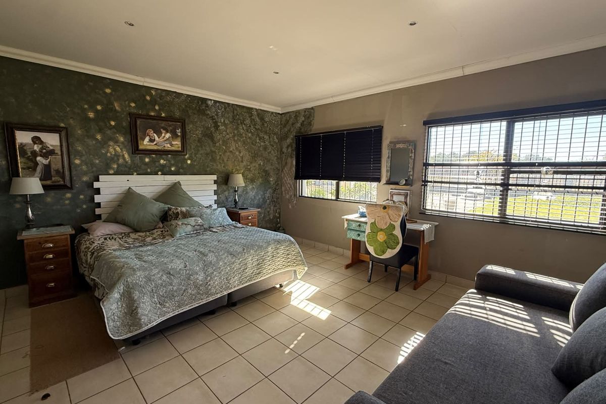 Spacious bedroom featuring tiled flooring, large windows with security bars, and a decorative feature wall.