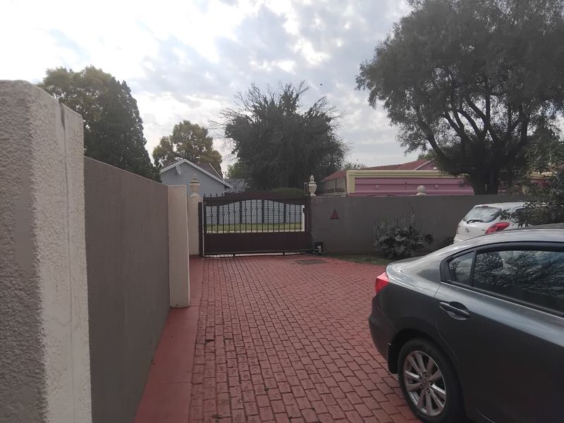 A view of the property entrance featuring a paved driveway, boundary wall, and a secure automated gate.