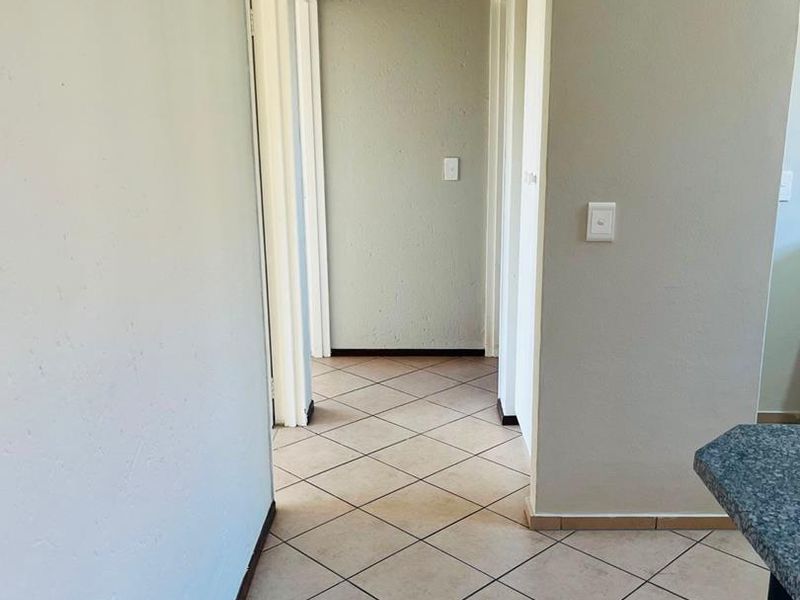 A clean, empty hallway featuring neutral wall tones and tiled flooring, providing access to multiple rooms within the townhouse.