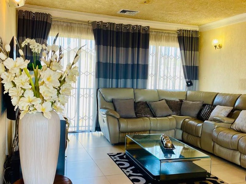 A comfortable living room featuring tiled flooring, air conditioning, and large sliding glass doors with security gates, providing access to the exterior.