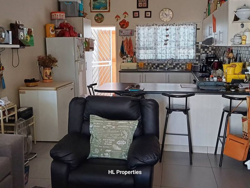 Open plan living area featuring a functional kitchen with breakfast bar, tiled flooring, and direct access to the exterior.