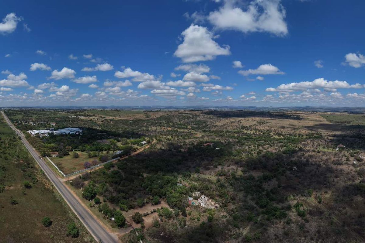 A wide-angle aerial view showing the surrounding landscape, rural terrain, and road access near the property.