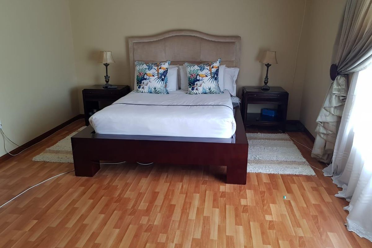 A well-lit bedroom featuring wood-look laminate flooring and neutral wall tones, providing a comfortable and functional sleeping space.