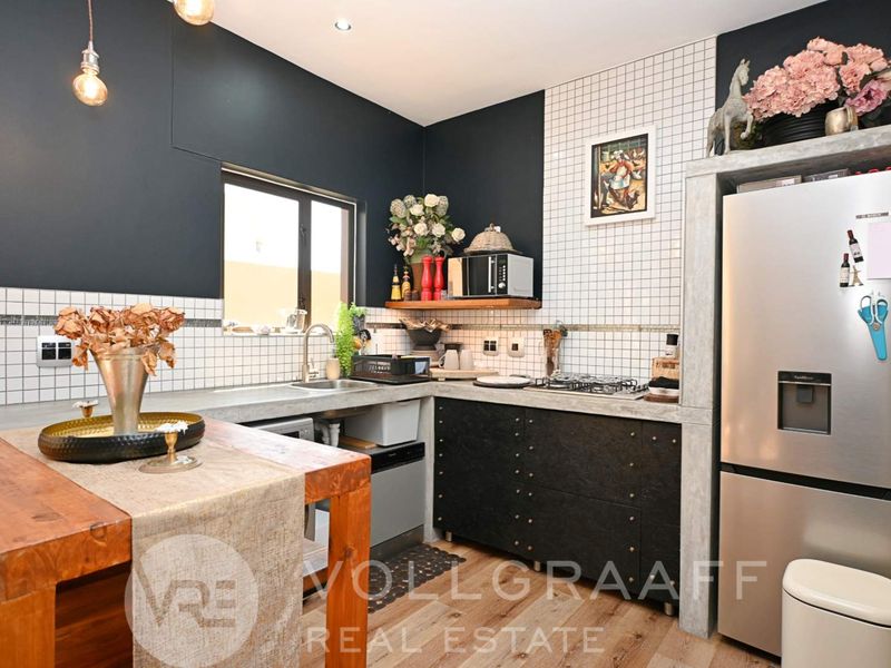 Modern kitchen featuring concrete countertops, tiled backsplash, gas hob, and dark cabinetry with integrated storage solutions.
