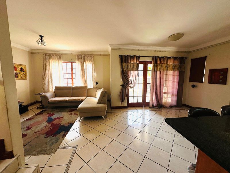 Open plan living area featuring tiled flooring, coving, and direct access to the exterior through classic french doors.