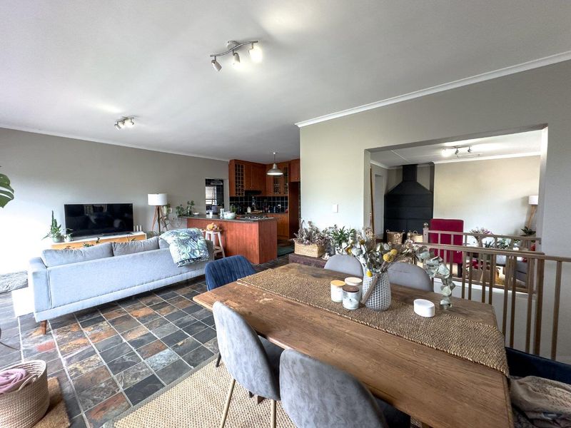 Open-plan living and dining area featuring slate tile flooring, a central kitchen island with wooden cabinetry, and a built-in fireplace.
