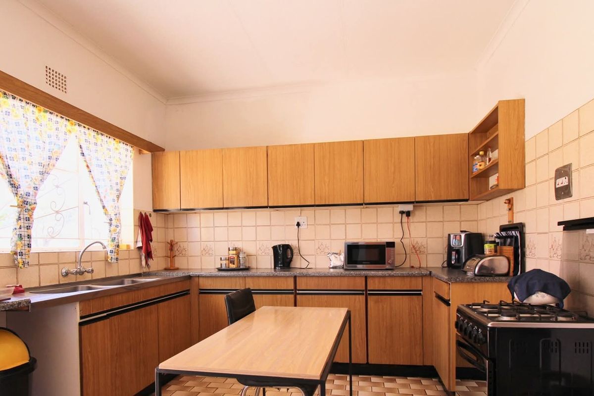 A functional kitchen featuring wood-look laminate cabinetry, tiled splashbacks, and a freestanding gas stove, offering a practical layout with ample storage space.