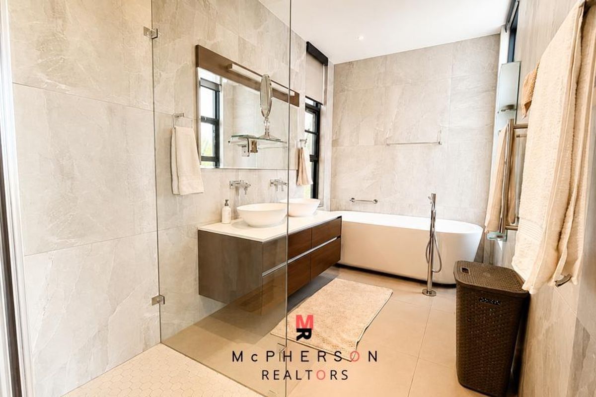 Modern bathroom featuring a double vanity, a sleek freestanding bathtub, and a spacious walk-in shower with floor-to-ceiling neutral tiling.