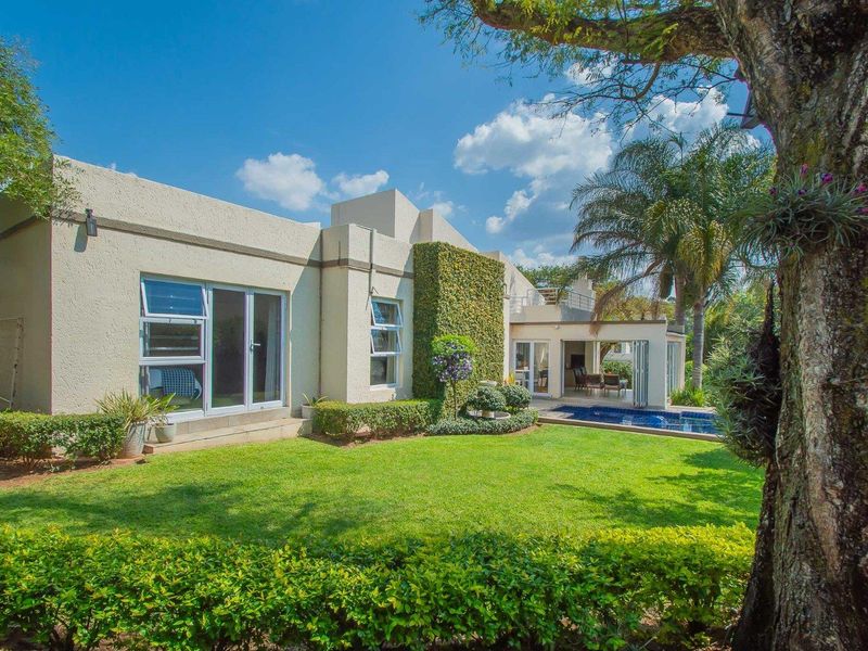 Rear view of the cluster home featuring a well-maintained garden, a swimming pool, and a covered patio area with sliding glass doors.