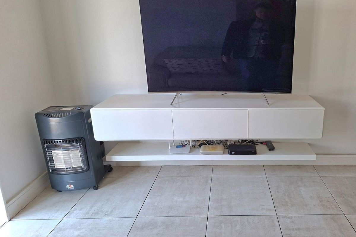 A living room area featuring a wall-mounted white media console and neutral tiled flooring.