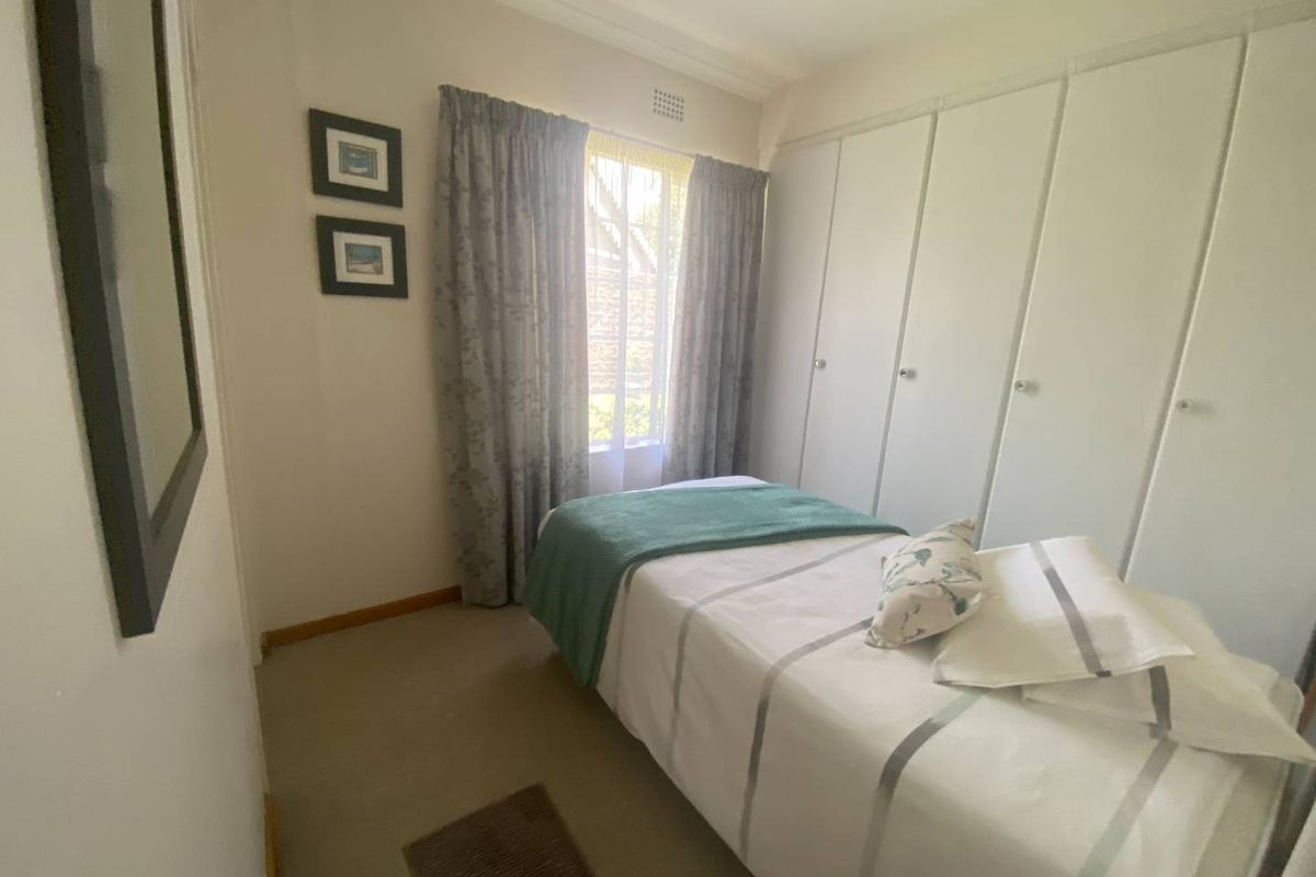 A compact bedroom featuring built-in floor-to-ceiling cupboards and neutral carpeting, providing functional storage and a comfortable living space.