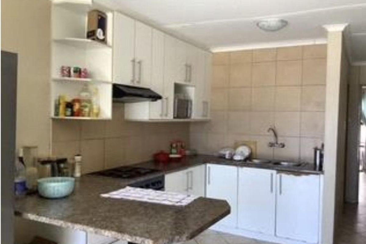 Functional kitchen featuring white cabinetry, laminate countertops, a built-in hob and oven, and a tiled backsplash with a double sink.