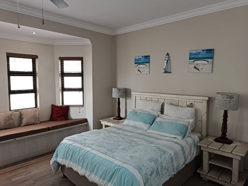A well-maintained bedroom featuring a cozy bay window with a built-in window seat, laminate flooring, and crown molding.