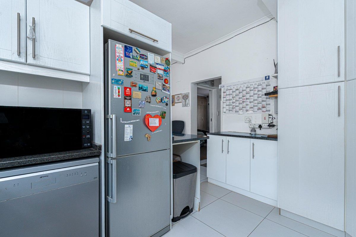 A functional kitchen area featuring white cabinetry, dark countertops, and tiled flooring, providing efficient storage and workspace.