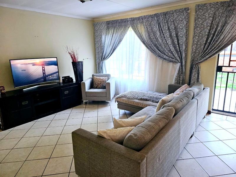 A living room featuring ceramic tiled flooring and a sliding glass door providing access to the exterior.