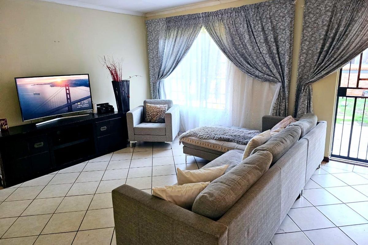 A living room featuring ceramic tiled flooring and a sliding glass door providing access to the exterior.