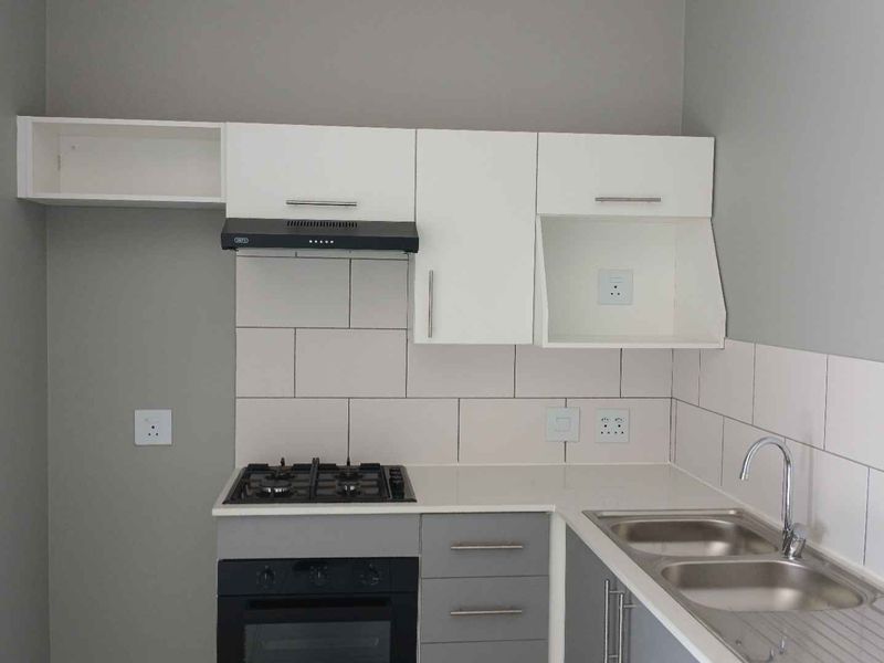 Modern kitchen featuring built-in cabinetry, stone countertops, a gas hob with extractor fan, and a double bowl stainless steel sink with tiled splashback.