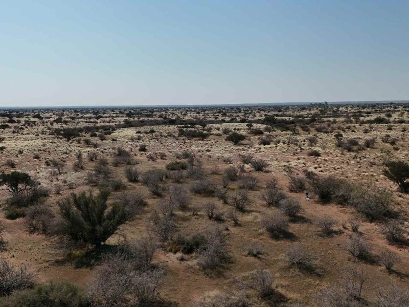 An aerial view of the expansive, arid farm landscape featuring natural vegetation and open terrain.